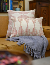 Load image into Gallery viewer, Two Terracotta cushion cover sizes on an ivory cotton base fabric placed on a cotton throw blanket on a couch